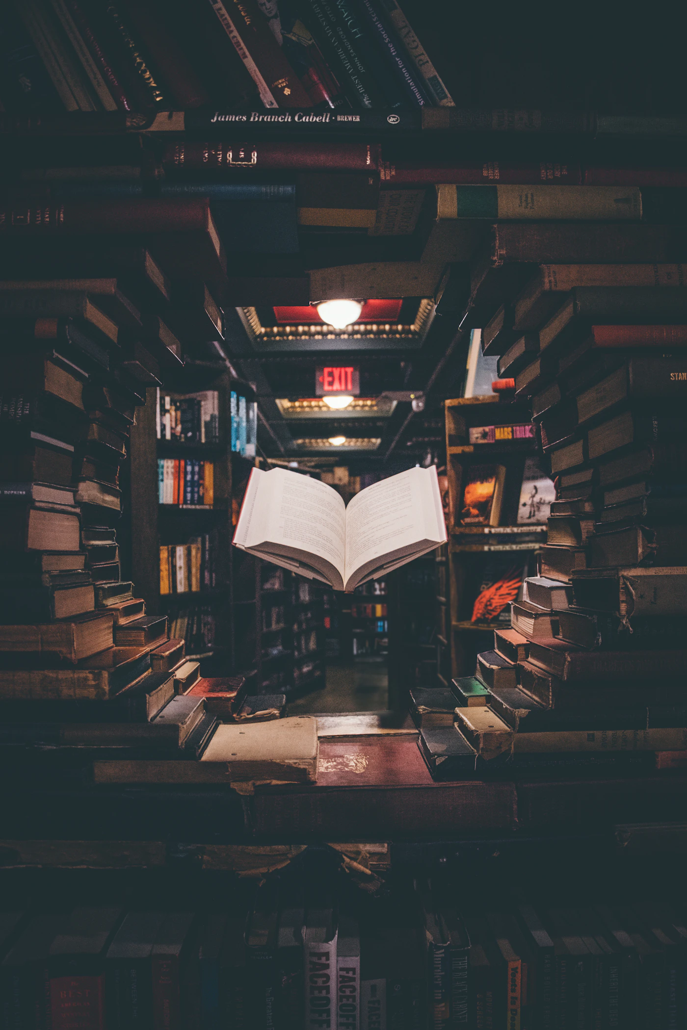 Estante de biblioteca com luz lateral, livros abertos sobre mesa de leitura